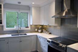 cool tones in white and grey are warmed up by subtle pot lights and creamy countertops