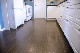 rich brown floors done in a porcelain tile that mimics hardwood floors and contrast perfectly against the white cabinets