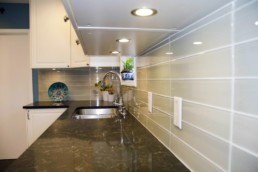 creamy green subway tiles line the backsplash in the kitchen