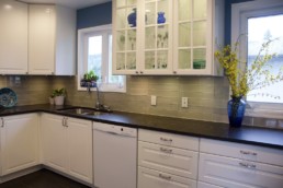 beautiful glass subway tile line the backsplash of this blue and white kitchen