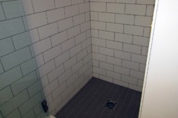 large white subway tile line the shower walls that contrast the dark grey floor tile