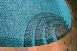 Precision work by Instyle Tilecraft Ltd. with this indoor swimming pool all glass tile finish in a mosaic blue pattern.