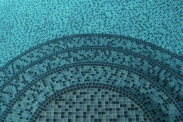 upclose of the swimming pool steps with a blue glass mosaic tile