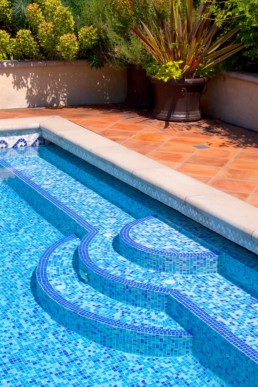 blue mosaic tile on pool steps contrasting beautifully against the terracotta deck tiles