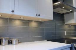beautiful glass subway tile in a blue-grey hue contrast perfectly against the white shaker style cabinets