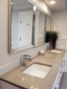 huge beveled mirrors above a silestone quartz counter-top in a modern white bathroom