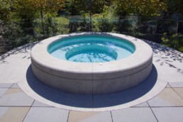 raised whirlpool with large concrete coping for extra seating and glass tile finish