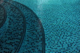 upclose side view of an inviting blue glass mosaic pool tile